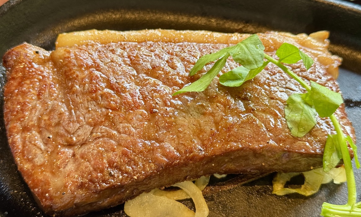 A perfectly grilled Shimofuri Highlands Beef sirloin steak on a hot plate